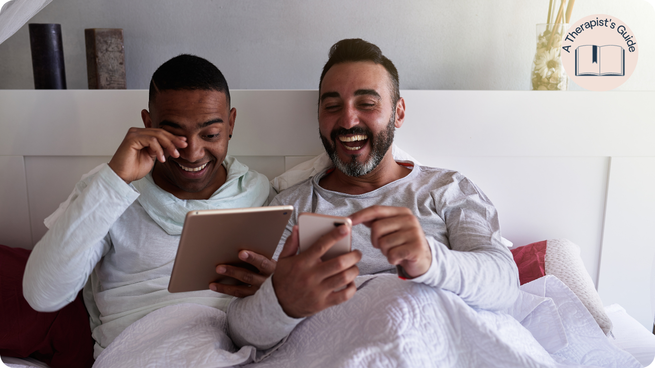 two men in bed laughing at content on phone